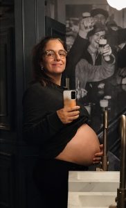Mariana embarazada de 38 semanas posando frente al espejo con la panza descubierta.